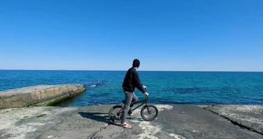 jovem macho com skate relaxante perto do mar foto