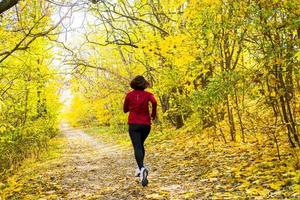 jovem corredor de mulher feliz treinando no ensolarado parque de outono foto