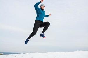 jovem corredor masculino treinando ao ar livre em tempos de inverno, homem correndo na neve foto