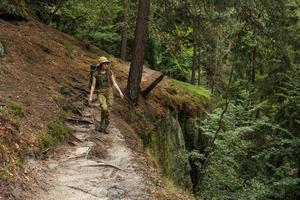 jovem caminhando no prado de primavera, montanhas e floresta no fundo foto