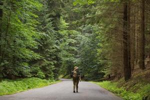 alpinista jovem caminhando na estrada estreita pela floresta verde de verão foto