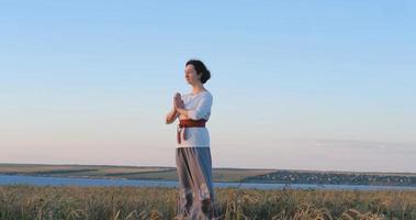 mulher praticando qigong em campos de verão com belo pôr do sol no fundo foto