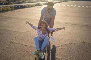 casal jovem feliz andando de skate durante o nascer do sol foto