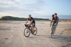 dois jovens do sexo masculino em uma bicicleta de turismo com mochilas e capacetes no deserto em uma viagem de bicicleta foto