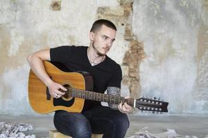 jovem macho com guitarra no quarto vazio, músico e compositor sozinho no estúdio foto