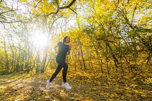 jovem corredor de mulher feliz treinando no ensolarado parque de outono foto