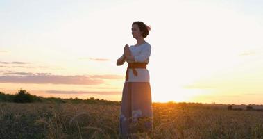 mulher praticando qigong em campos de verão com belo pôr do sol no fundo foto