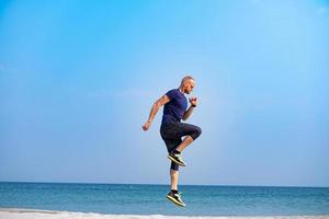 jovem atleta masculino treinando em dia ensolarado na praia foto