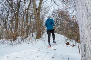 jovem corredor masculino treinando ao ar livre em tempos de inverno, homem correndo na neve foto