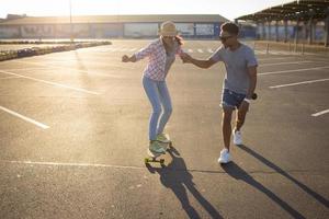 casal jovem feliz andando de skate durante o nascer do sol foto