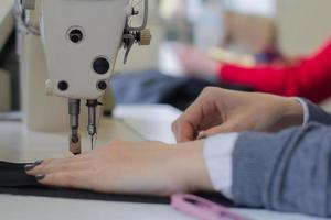 costureira no trabalho na mesa, alfaiate trabalha em estúdio com roupas foto