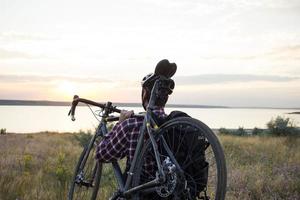 turista de bicicleta com mochilas e capacete viaja no deserto em sua bicicleta ciclocross durante o pôr do sol foto