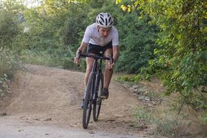 ciclista em passeio de bicicleta de ciclocross profissional em declive, pinheiro e fundo do lago foto