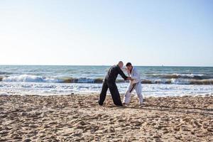 lutadores de karatê estão lutando no ringue de boxe de praia de manhã foto