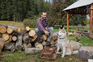 turista relaxando na madeira picada com cachorro husky e bebendo chá ou café foto