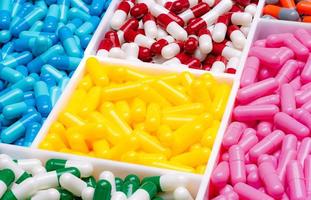pílulas de cápsula multicoloridas em caixa de plástico. conceito de vitaminas e suplementos. indústria farmacêutica. medicamentos prescritos em bandeja de plástico. pílulas de cápsula amarela, rosa, azul, verde, vermelha, branca e laranja. foto