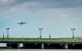 avião de passageiros decola no aeroporto com lindo céu azul e nuvens. saindo do voo. iniciar a viagem ao exterior. férias. cerca e painéis de células solares no aeroporto. canal de drenagem e tubulação. foto