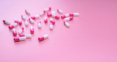 pílula de cápsulas de antibiótico rosa-branco espalhada no fundo rosa. bandeira de farmácia. conceito de resistência a antibióticos. pílulas e conceito de amor. indústria farmacêutica. Farmácia e seguros de saúde. foto
