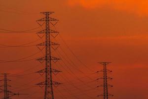 poste elétrico de alta tensão e linhas de transmissão à noite. postes de eletricidade ao pôr do sol. potência e energia. conservação de energia. torre de grade de alta tensão com cabo de arame na estação de distribuição. foto