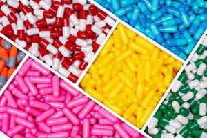 comprimidos de cápsula de vista superior em caixa de plástico. comprimidos em cápsulas amarelo, rosa, azul, vermelho-branco, verde-branco e laranja-cinza. indústria farmacêutica. pílulas de cápsula de antibiótico, vitaminas e suplementos. foto