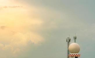 estação de cúpula de radar de observações meteorológicas e torre de telecomunicações contra céu azul e nuvens. uso de torre de estação de observações meteorológicas aeronáuticas para aeronaves de segurança em negócios de aviação. foto