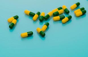 cápsulas verde-amarelas espalhadas sobre fundo azul. pílulas de cápsula de tramadol para aliviar a dor severa do câncer. remédio analgésico. droga opióide. produto farmacêutico para tratamento da dor. medicamento prescrito.