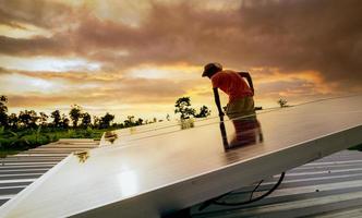 homem verificando o painel solar no telhado para segurança. manutenção de painéis solares ou módulos fotovoltaicos. recursos sustentáveis e energia renovável. energia solar para energia verde. estilo de vida sustentável. energia limpa foto