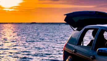 carro suv compacto preto com esporte e design moderno estacionado na estrada de concreto à beira-mar ao pôr do sol. tecnologia amiga do ambiente. viagem de viagem de férias na praia e caminhão de carro aberto foto