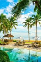 belo guarda-sol de luxo e cadeira ao redor da piscina ao ar livre em hotel e resort com coqueiro no céu do pôr do sol