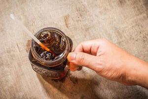 mão segurando de coca-cola no copo com gelo na tabel foto