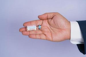 vacina covid-19 corona vírus na mão homem de negócios de terno azul sobre fundo branco. conceito de cuidado atencioso.