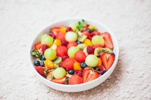 salada de primavera de frutas saudáveis. conceito de dieta saudável. deliciosas frutas frescas na tigela. foco seletivo. vista do topo. frutas coloridas misturadas em salada caseira. conceito de nutrição foto