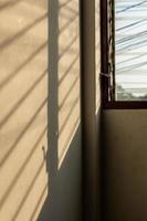 sombra da luz do sol na parede com janelas de persianas antigas. foto