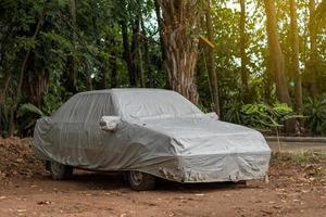 lona cinza cobrindo o velho sedan no chão. foto