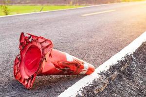 o cone de borracha laranja foi destruído, caindo em uma estrada pavimentada. foto