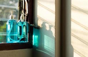 close-up de dois frascos de spray de álcool na janela da persiana. foto