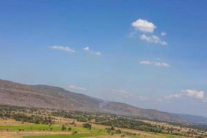 uma vista panorâmica das colinas com aldeias, árvores e campos de arroz com nuvens no céu. foto