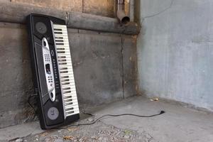 um velho sintetizador musical abandonado fica perto da parede de um prédio na rua foto