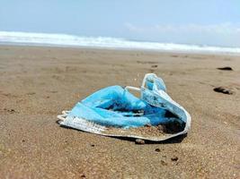 máscaras usadas que viram lixo na praia foto