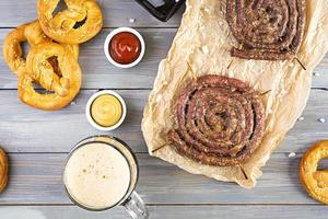 menu de comida para oktoberfest. salsicha com molho diferente, pretzel e copo de cerveja escura foto