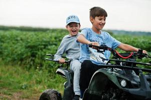 dois irmãos dirigindo quadriciclo de quatro rodas. momentos felizes das crianças. foto
