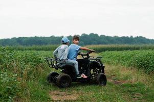 dois irmãos dirigindo quadriciclo de quatro rodas. momentos felizes das crianças. foto