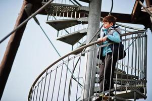 menino fica na escada em espiral na torre de observação. foto