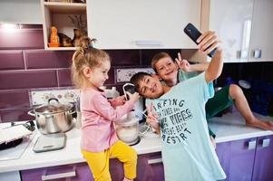 crianças cozinhando na cozinha, momentos felizes das crianças. fazendo selfie no telefone. foto