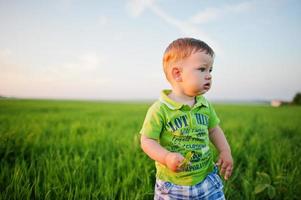 menino bonito no campo de grama verde à noite. foto