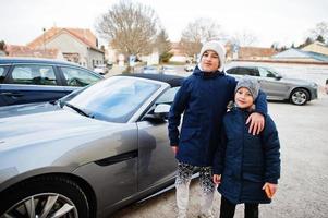 dois irmãos abraços perto de carro de luxo esporte. foto