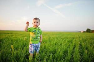 menino bonito no campo de grama verde à noite. foto