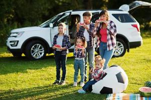 família passar tempo juntos. quatro filhos com mãe comem melancia ao ar livre. foto