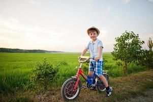 menino usa chapéu em bicicleta, momentos de crianças felizes. foto