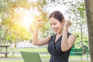 close-up de eufóricas mulheres bonitas celebrando o sucesso nos negócios lendo boas notícias no laptop no parque foto